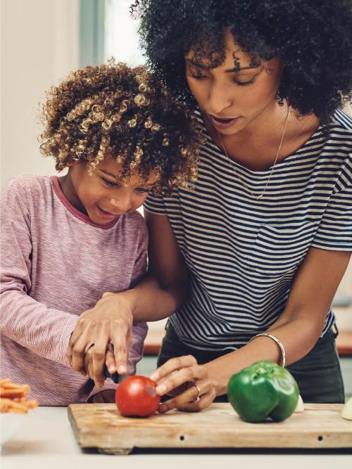 LP-MotherSonCooking Mother showing her son how to cut various vegetables on a cutting board