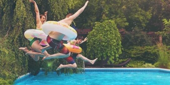 Summertime Family Fun Jumping Into a Pool with Floaties On