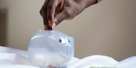 Saving money by placing coins in a clear piggy bank