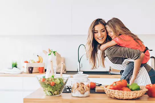 A mother plays in the kitchen with her daughter with the carefree confidence of Check Into Cash personal loans and financial services